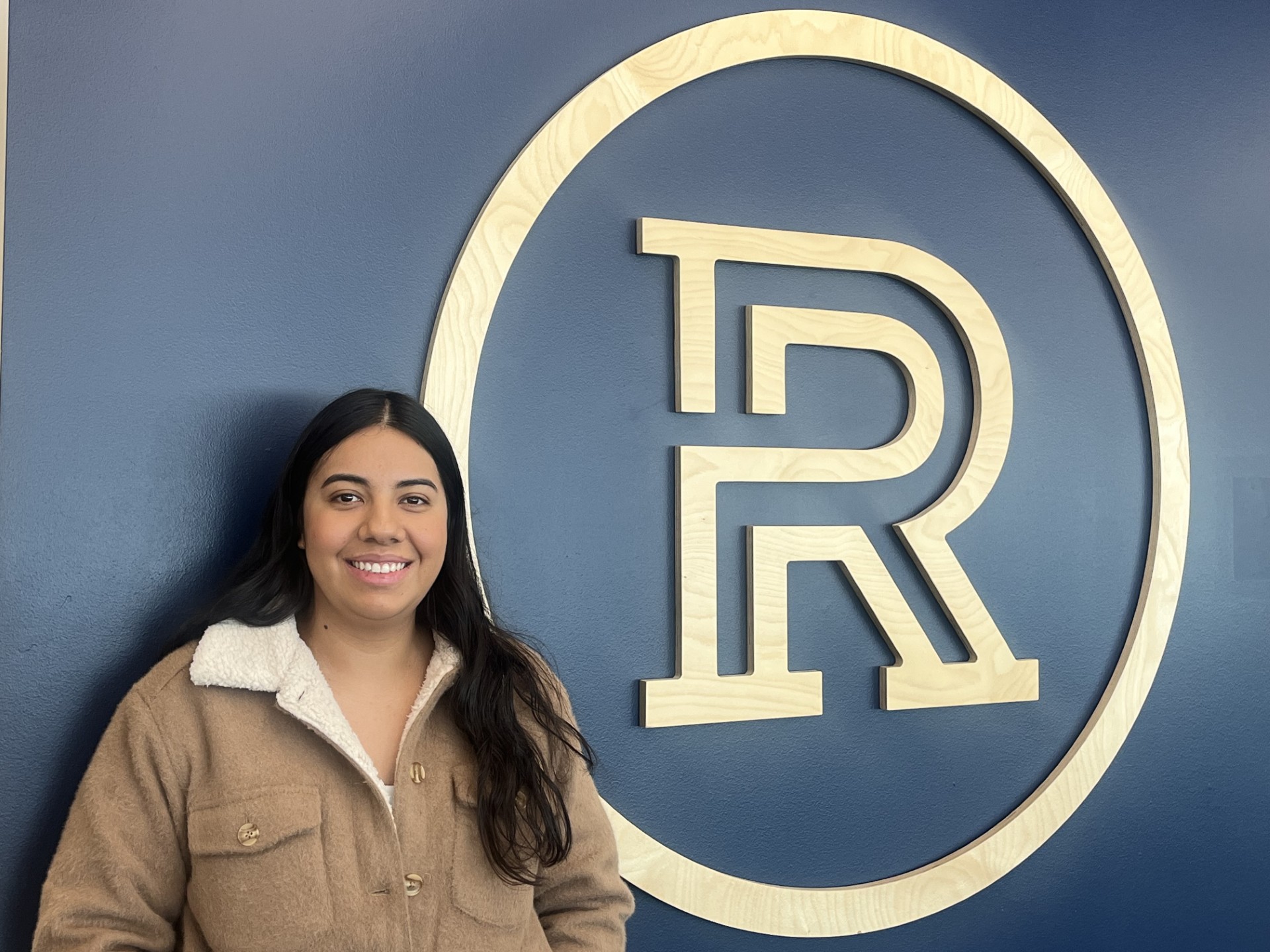 Mariana Lemus Lara - Standing by a wall with the Riverland Logo