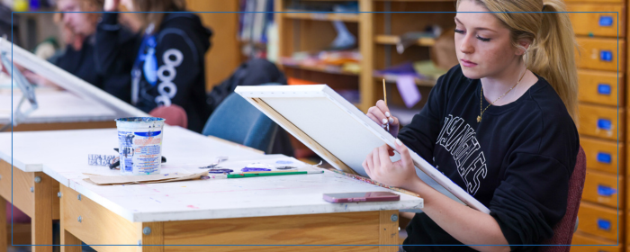 Student painting on canvas in an art class