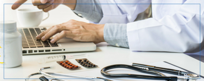 Healthcare professional studying or working at a laptop with medical tools on a desk